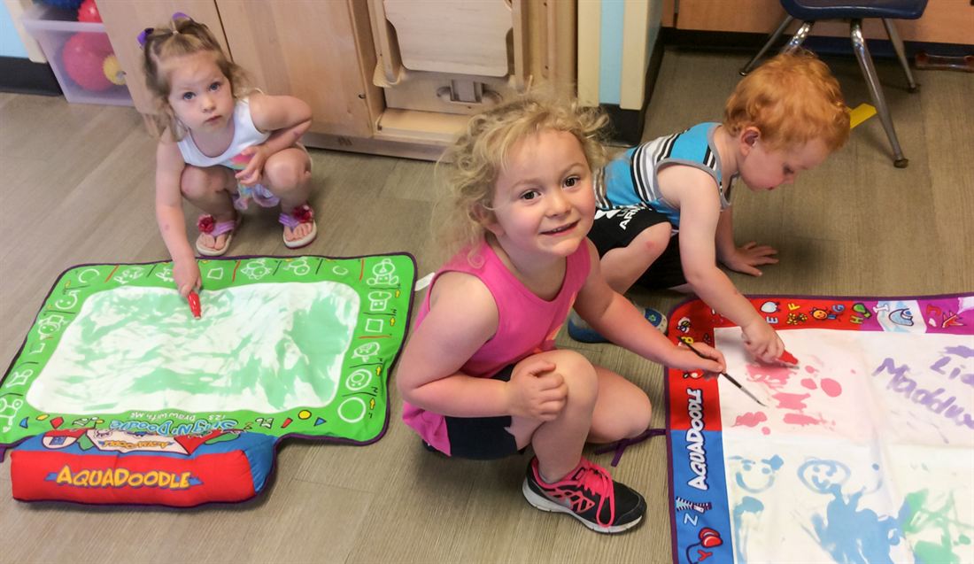 Children drawing on a floor mat